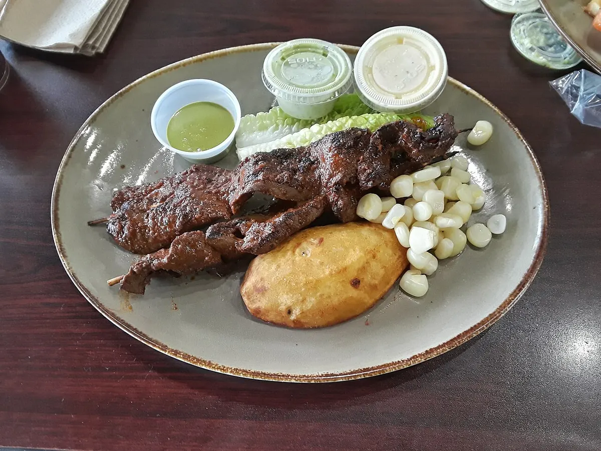 Anticuchos con papa dorada, choclo y cremas